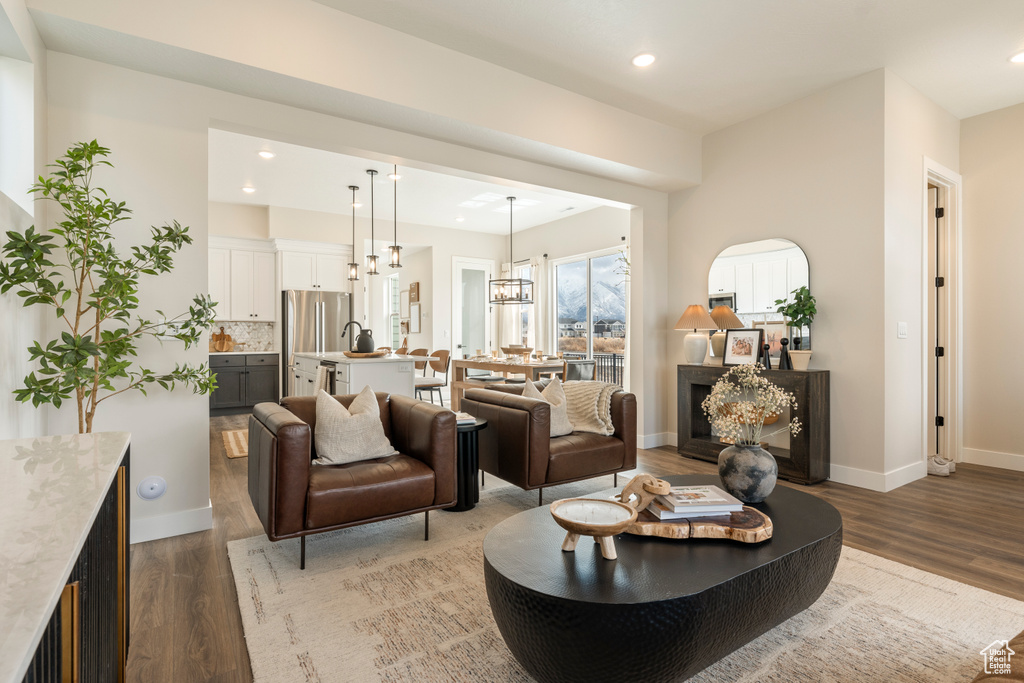 Living area with wood finished floors, a chandelier, baseboards, and recessed lighting