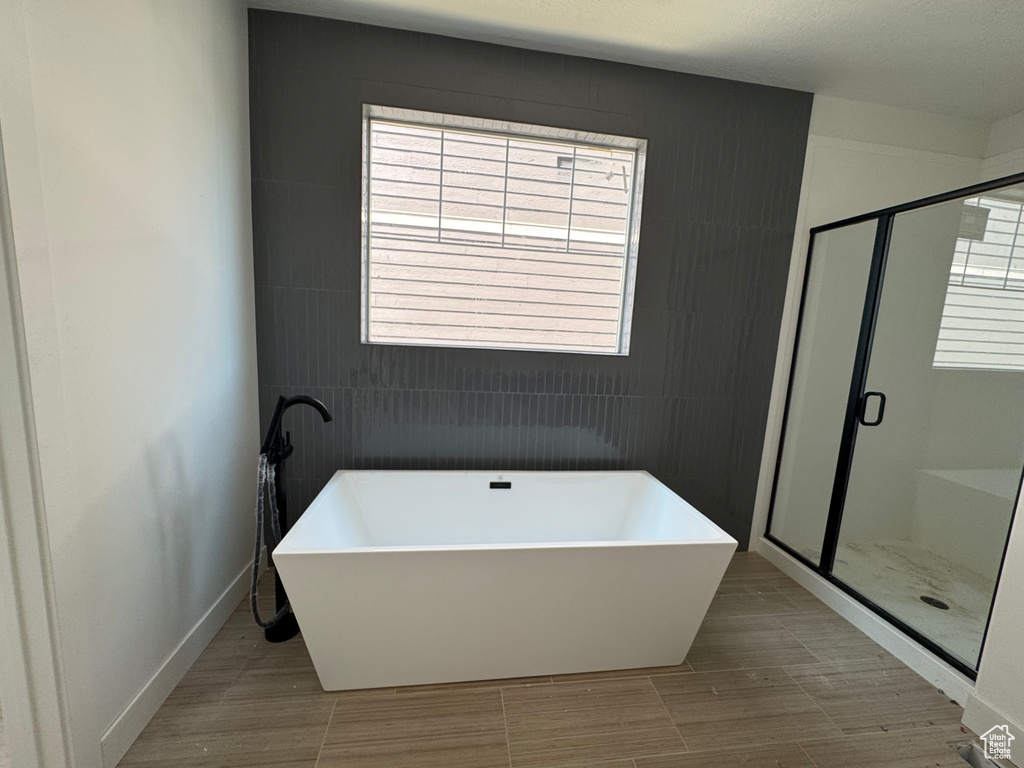 Full bathroom with a soaking tub, a stall shower, and tile walls