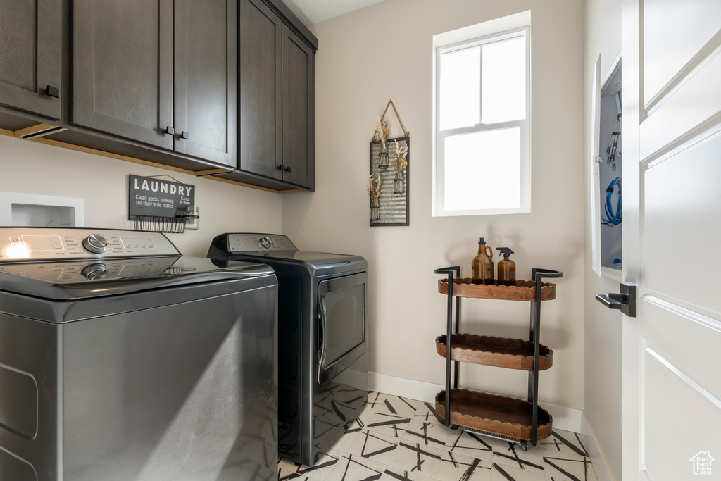 Clothes washing area with cabinet space, washing machine and dryer, and baseboards