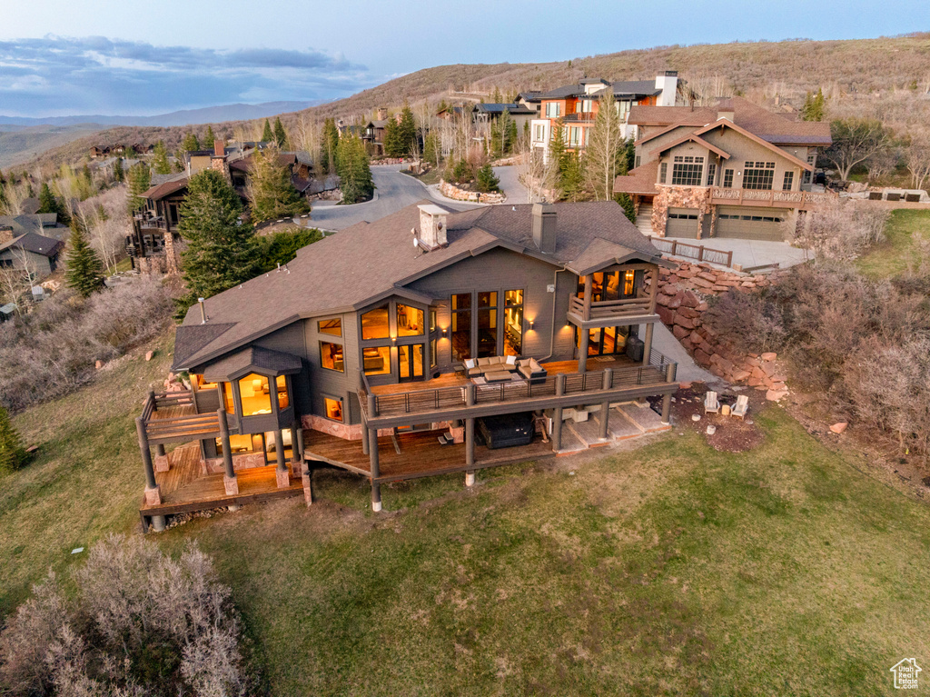 Back of property with a deck with mountain view, a garage, and a lawn