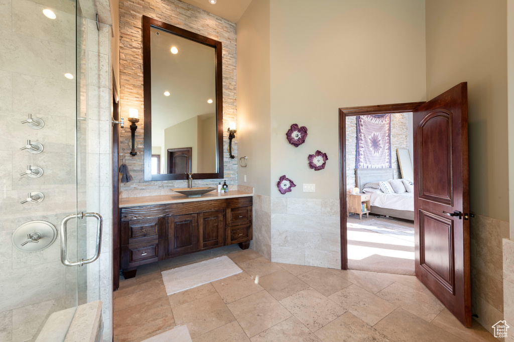 Ensuite bathroom with tile walls, vanity, a shower stall, a high ceiling, and wainscoting