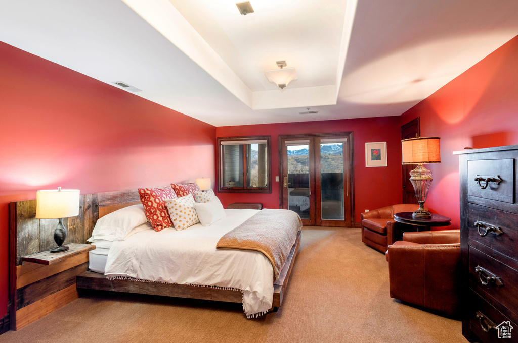 Carpeted bedroom with access to outside and a raised ceiling