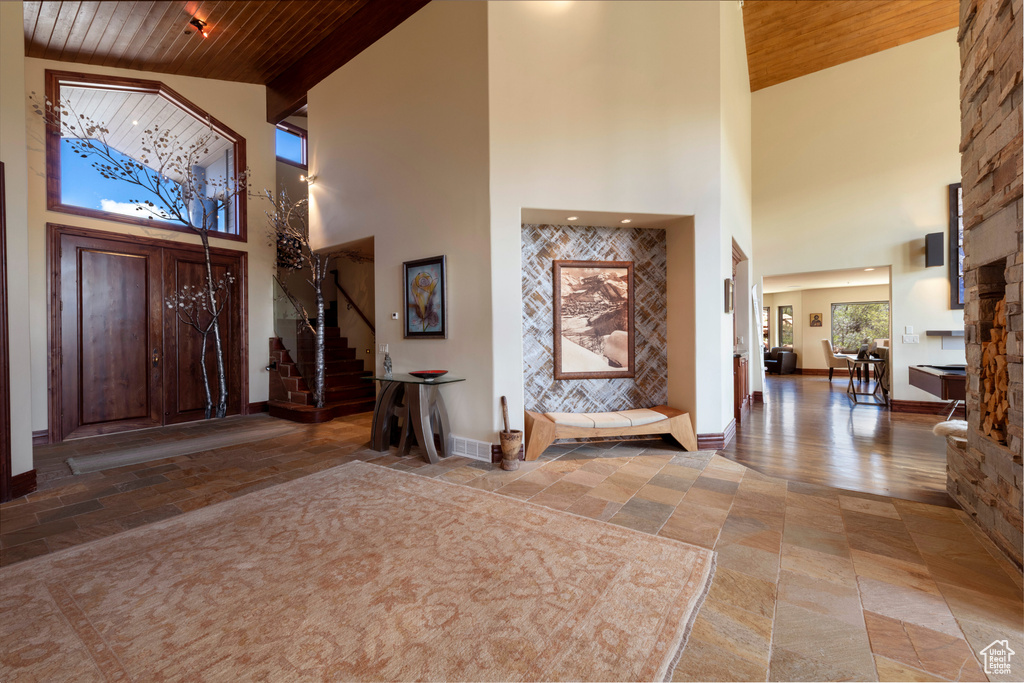 Entryway featuring high vaulted ceiling, stairway, wood ceiling, and baseboards