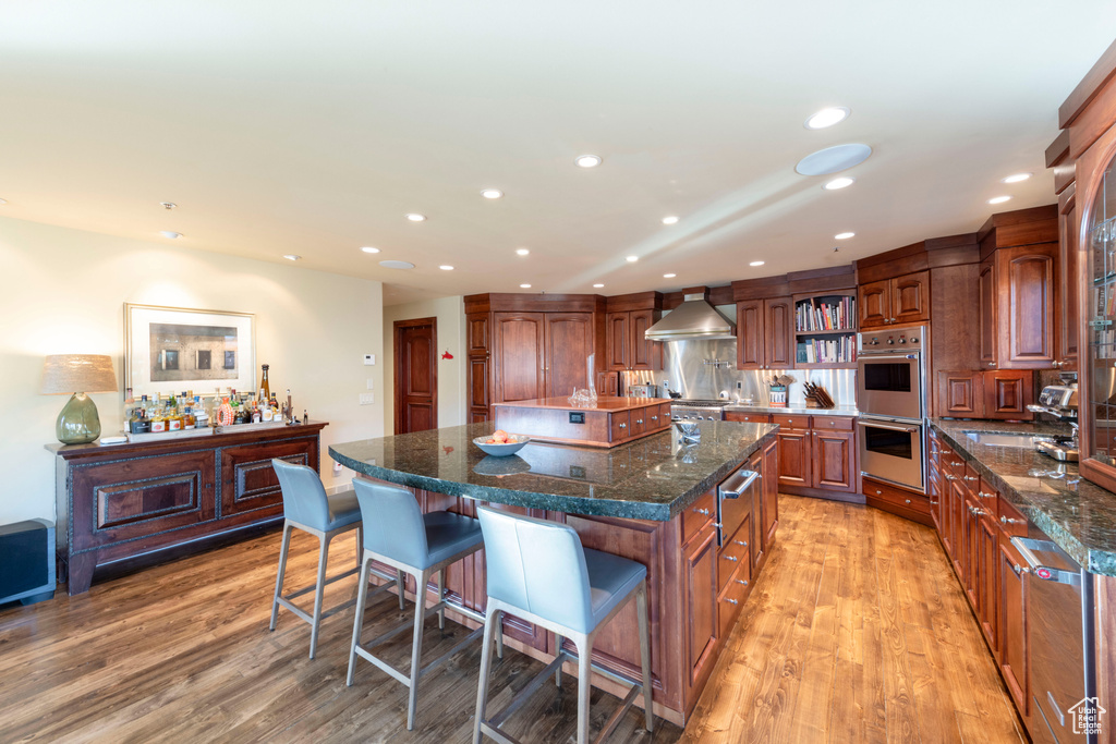 Kitchen with appliances with stainless steel finishes, a large island, recessed lighting, a breakfast bar, and light wood-type flooring