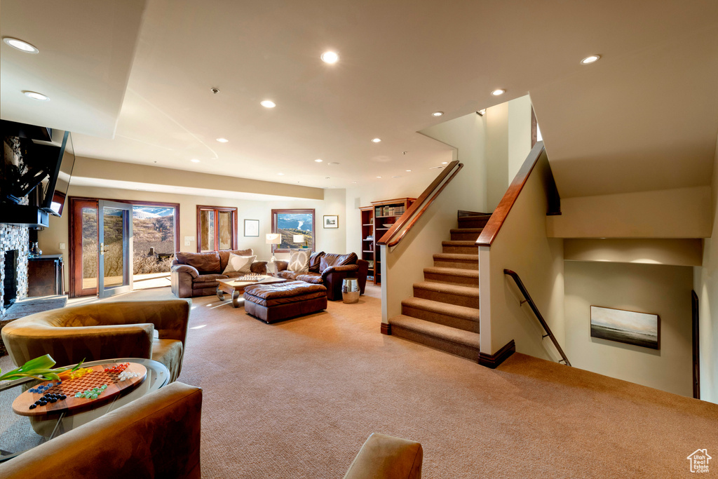 Living room featuring carpet, recessed lighting, a fireplace, and stairway