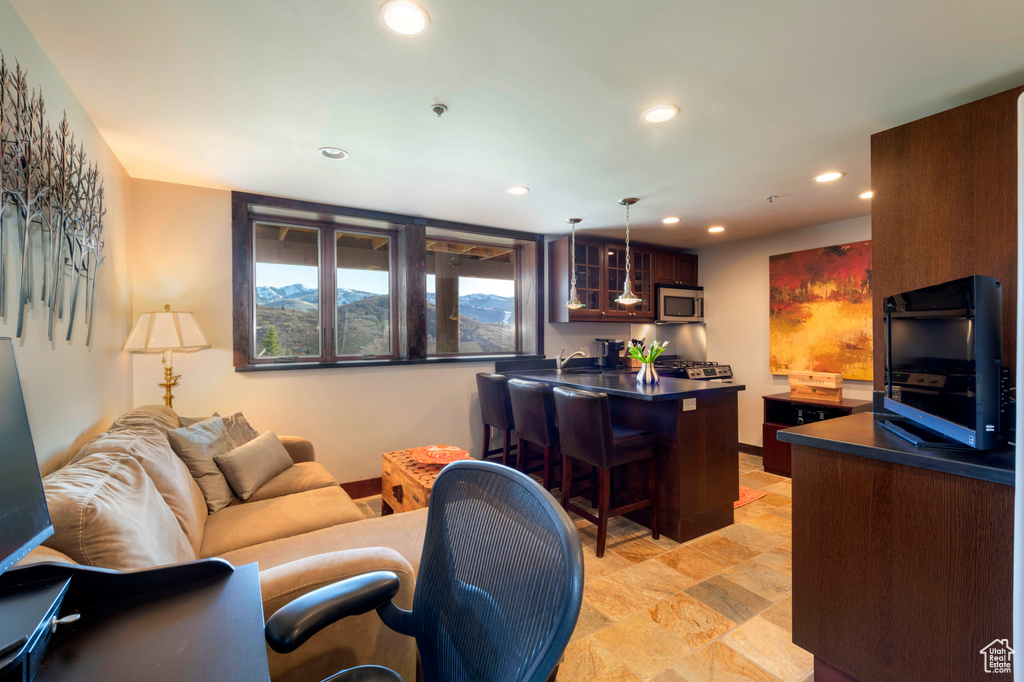 Living area featuring recessed lighting, light stone finish flooring, bar, and baseboards