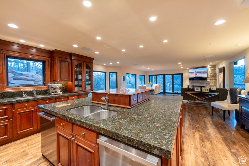 Kitchen featuring an island with sink, a sink, stainless steel dishwasher, recessed lighting, and light wood-style flooring