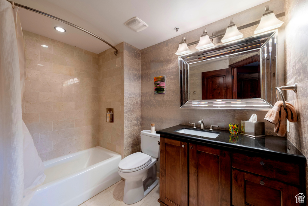Full bathroom featuring toilet, tile patterned floors, tile walls, vanity, and shower / bathtub combination with curtain