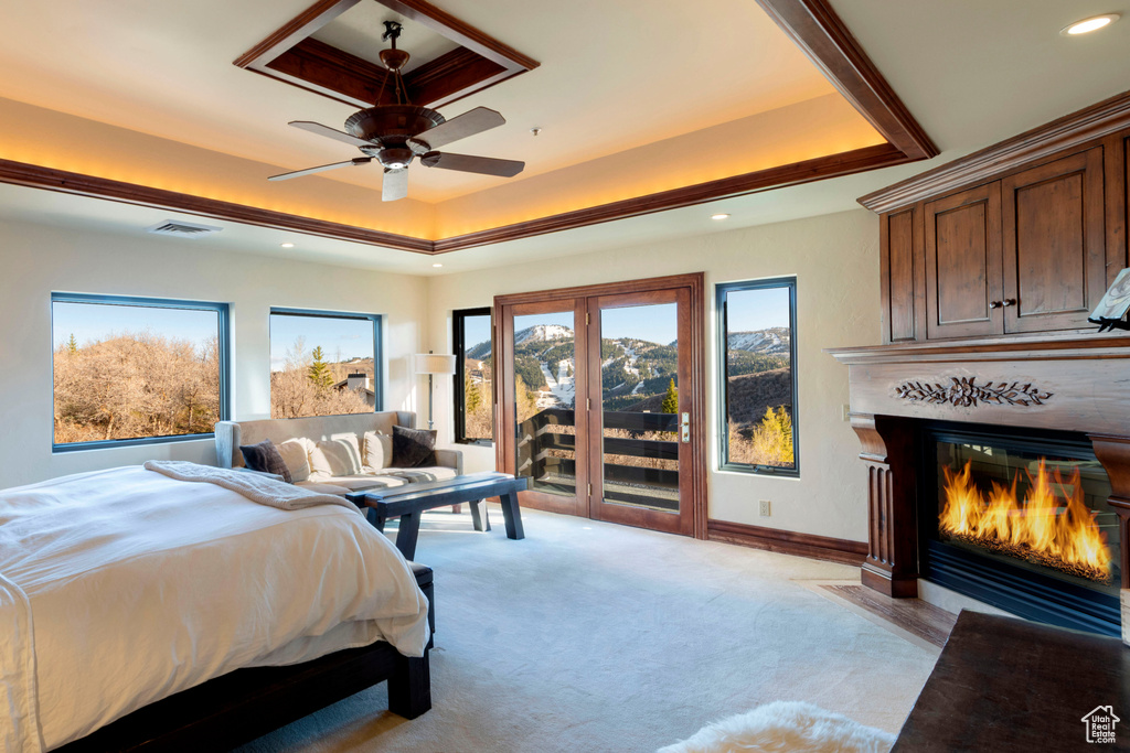 Bedroom with a tray ceiling, access to exterior, multiple windows, recessed lighting, and light carpet