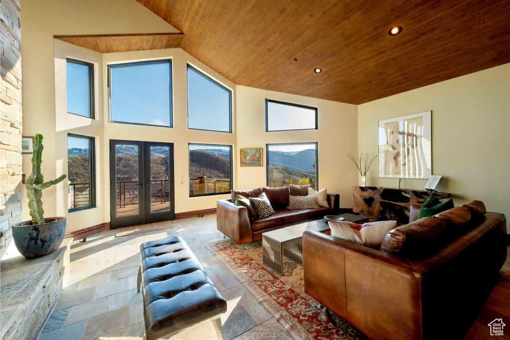 Living room featuring wood ceiling, stone tile floors, recessed lighting, high vaulted ceiling, and french doors