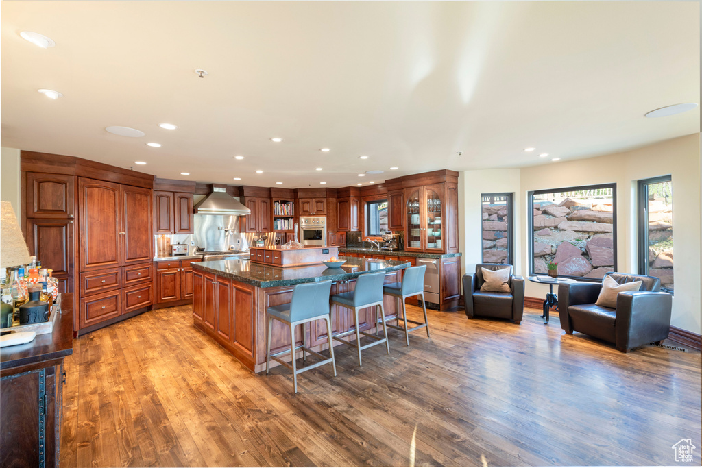 Kitchen featuring stainless steel oven, a spacious island, recessed lighting, light wood-style floors, and a breakfast bar