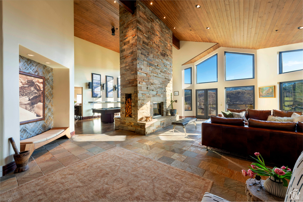 Living area with stone tile floors, high vaulted ceiling, wood ceiling, and recessed lighting