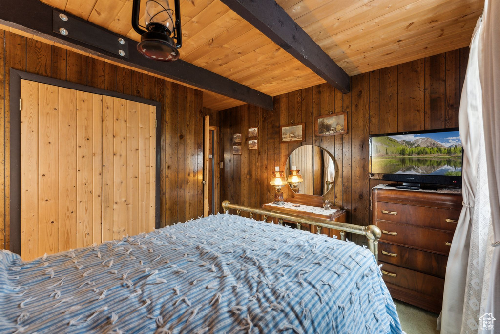 Carpeted bedroom featuring beamed ceiling, wooden ceiling, and wooden walls