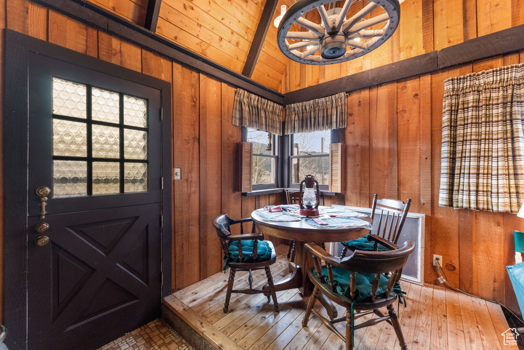 Dining room with wooden walls, a chandelier, wooden ceiling, and wood-type flooring