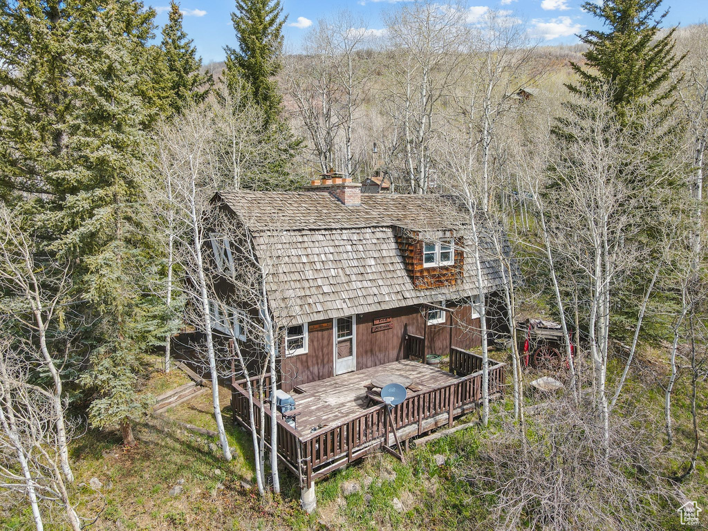 Back of house featuring a chimney and a wooden deck