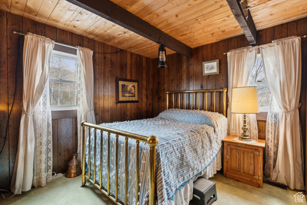 Carpeted bedroom with beam ceiling, wooden ceiling, and wood walls