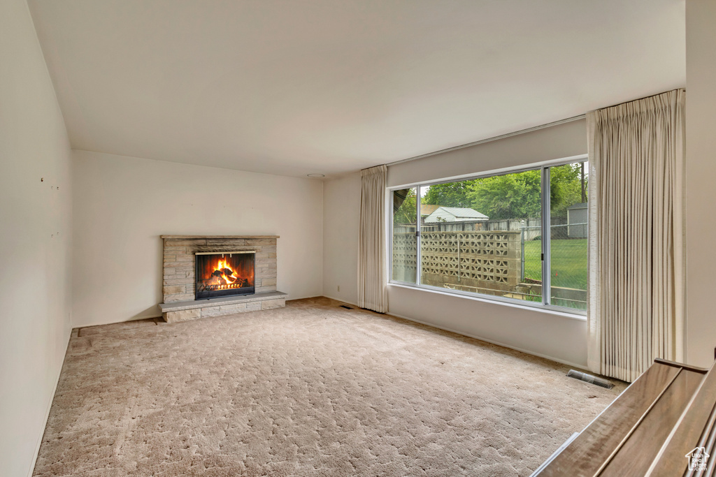 Unfurnished living room featuring a fireplace and carpet flooring