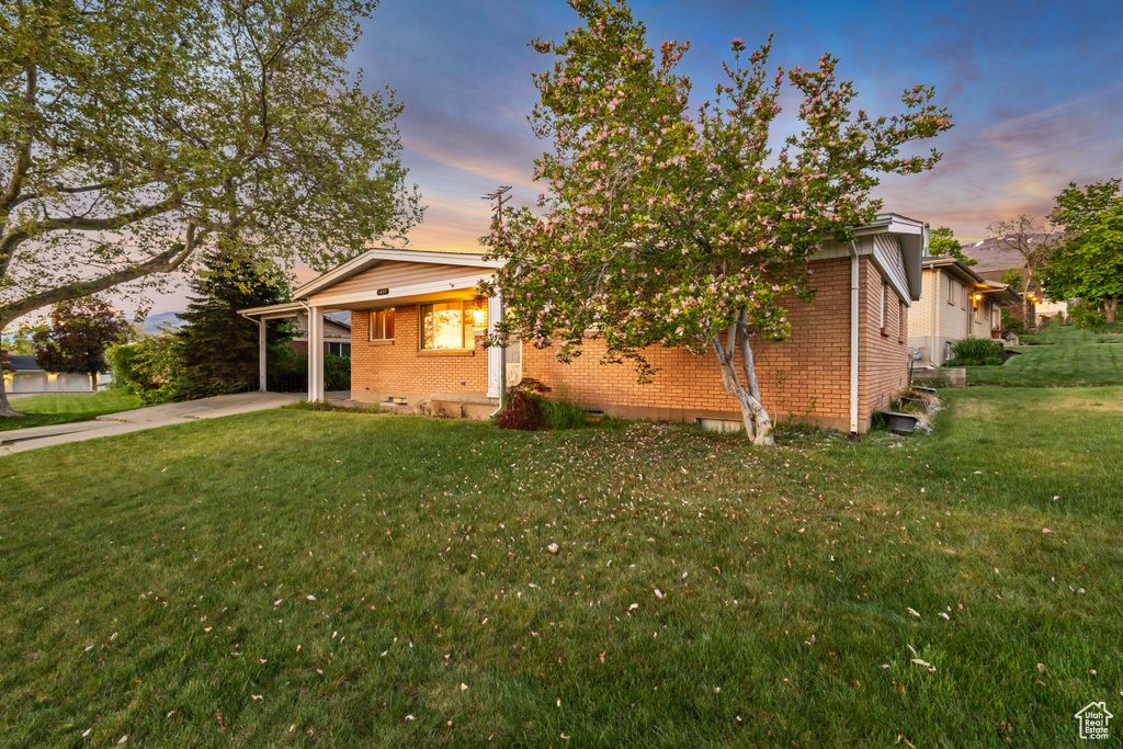 View of home\\\'s exterior with brick siding, a yard, concrete driveway, and an attached carport
