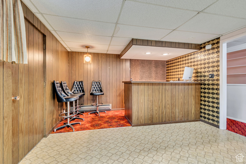 Indoor dry bar with a paneled ceiling, baseboards, and wooden walls