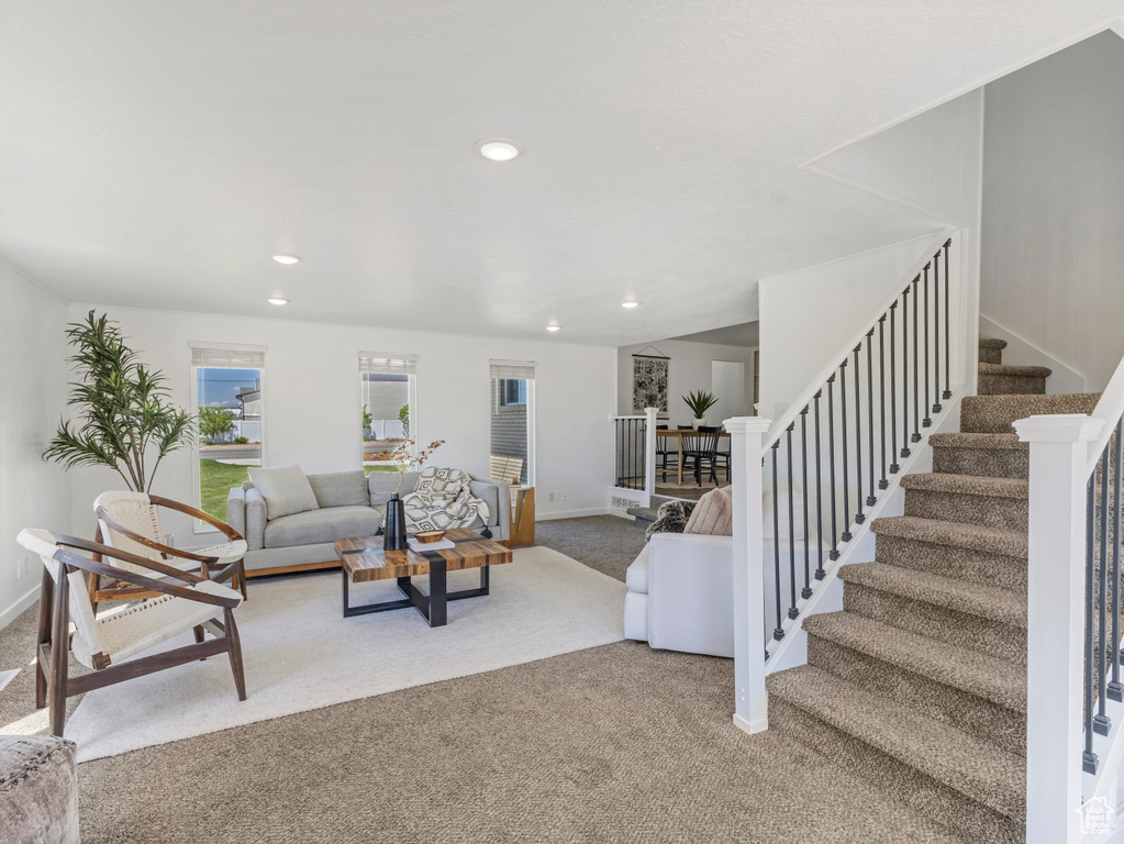 Carpeted living area featuring stairs, baseboards, and recessed lighting
