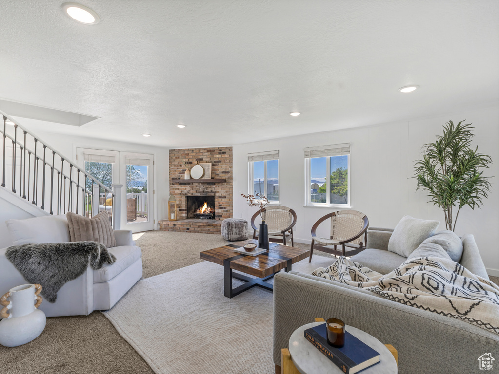 Living area featuring carpet, recessed lighting, a fireplace, and stairway
