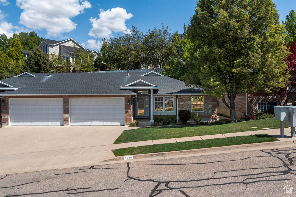 View of front of house with brick siding, a garage, driveway, a front yard, and a shingled roof