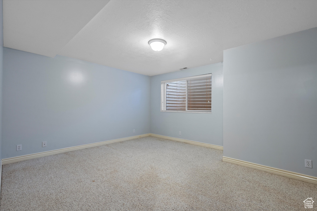 Spare room featuring carpet, baseboards, and a textured ceiling