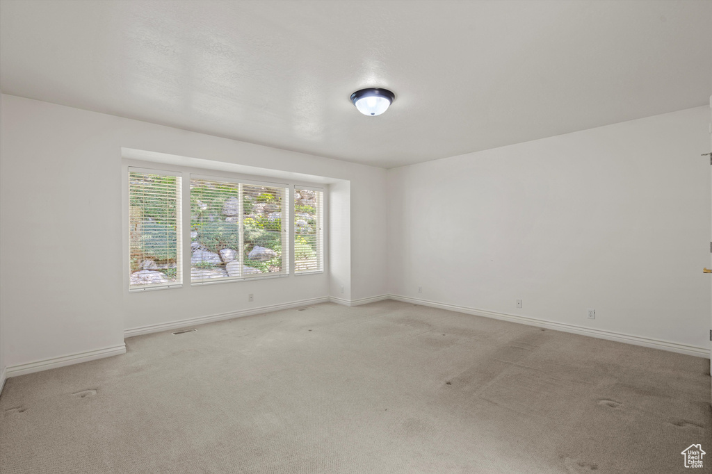 Unfurnished room featuring light carpet and baseboards