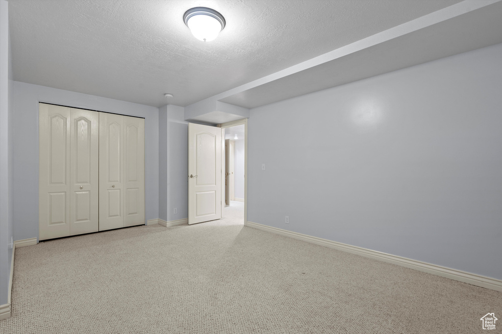 Unfurnished bedroom with baseboards, a textured ceiling, carpet floors, and a closet