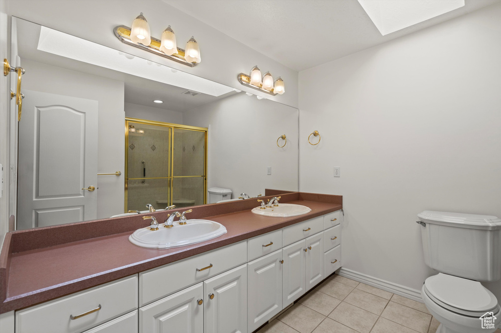 Full bath featuring toilet, a skylight, a stall shower, tile patterned floors, and baseboards