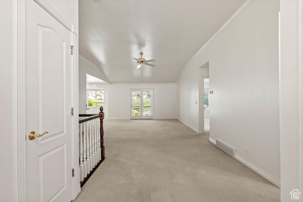 Hall featuring light carpet, baseboards, crown molding, an upstairs landing, and lofted ceiling