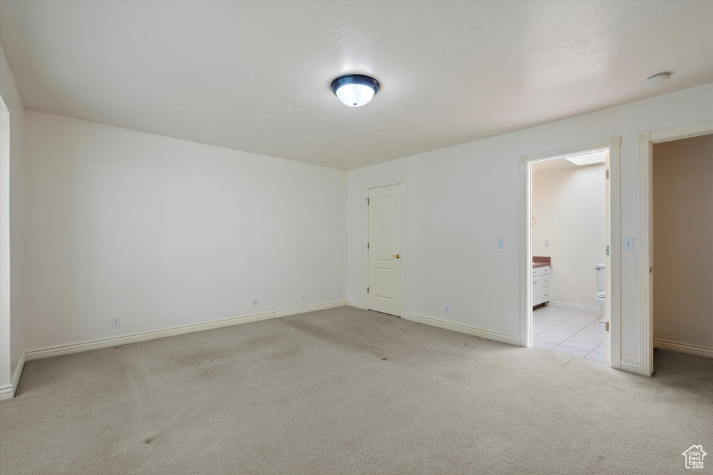 Unfurnished room featuring light carpet, baseboards, and a smoke detector
