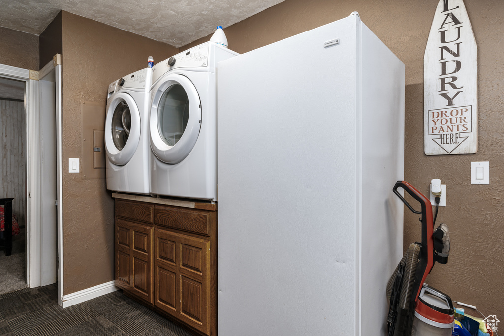 Laundry area featuring washing machine and clothes dryer, a textured wall, and dark tile patterned flooring