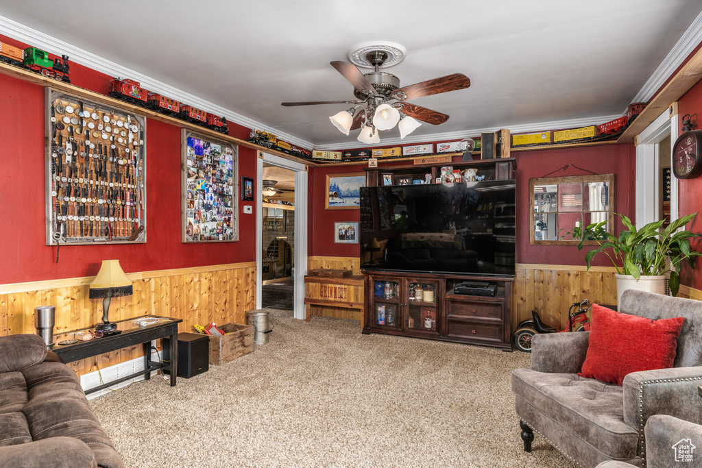 Living area featuring wainscoting, wooden walls, ceiling fan, carpet flooring, and ornamental molding