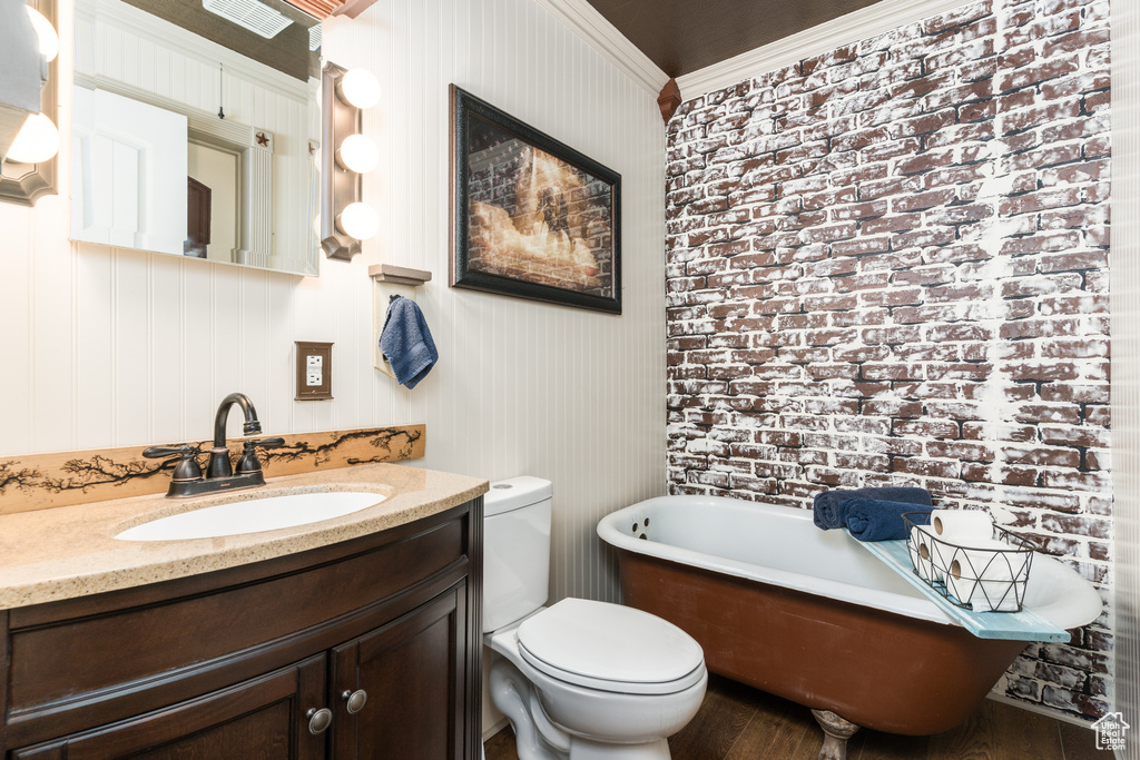 Full bathroom with toilet, vanity, a freestanding bath, and wood finished floors