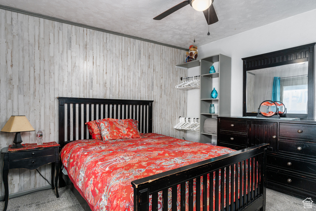 Carpeted bedroom with wood walls and ceiling fan