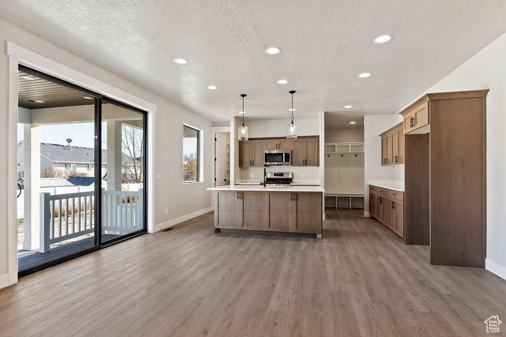 Kitchen featuring appliances with stainless steel finishes, light wood-type flooring, baseboards, recessed lighting, and a textured ceiling