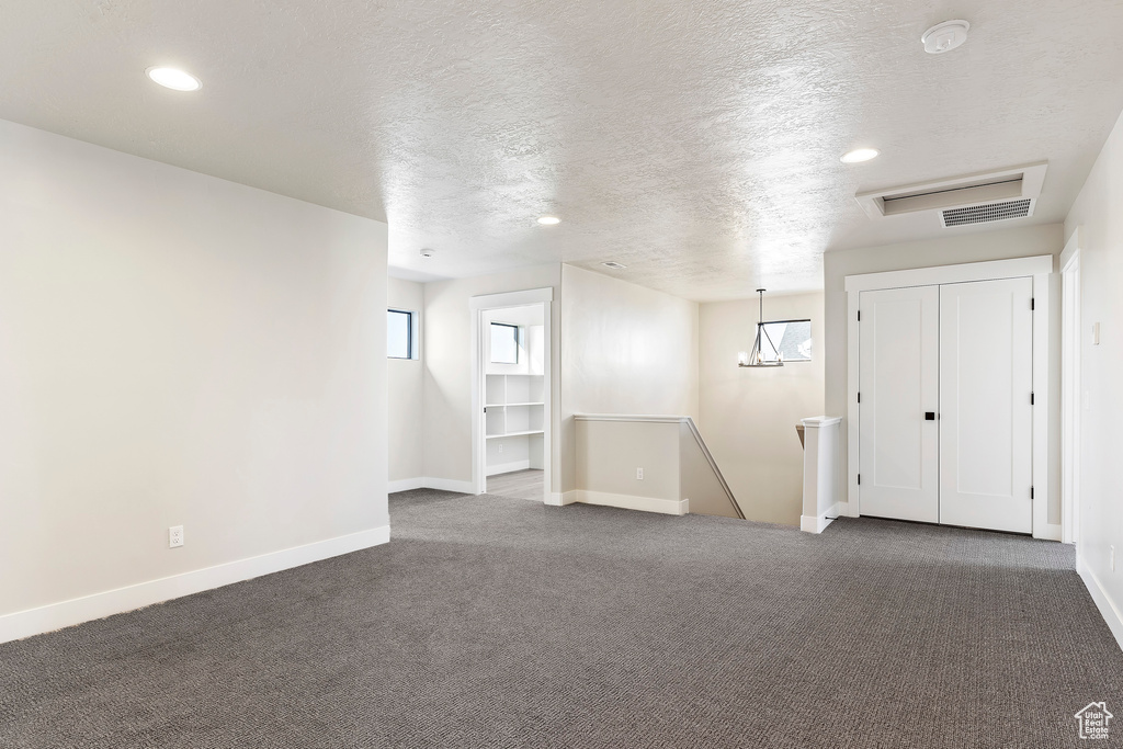 Basement with dark carpet, a textured ceiling, baseboards, and recessed lighting