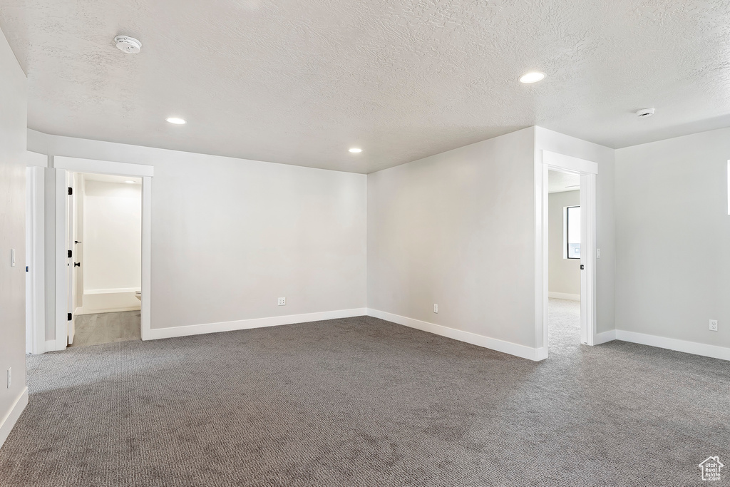 Unfurnished room featuring a textured ceiling, carpet, a smoke detector, recessed lighting, and baseboards