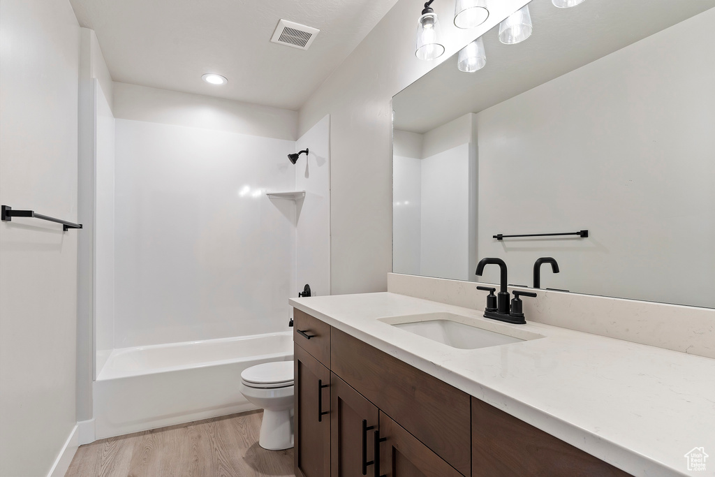 Bathroom featuring toilet, wood finished floors, vanity, and shower / tub combination