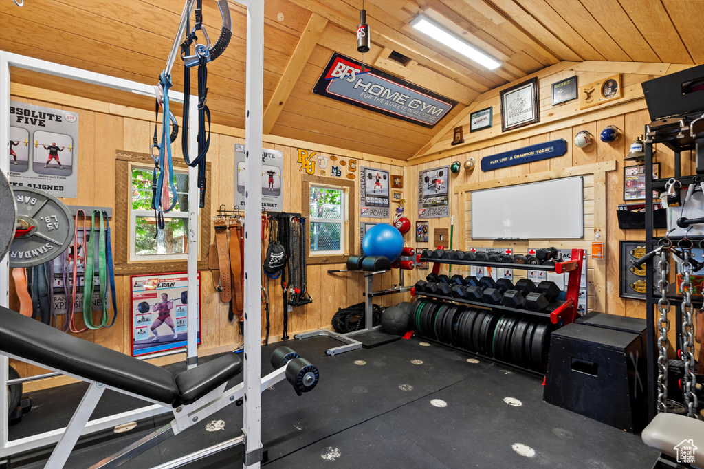Workout room featuring vaulted ceiling, wood walls, and wooden ceiling