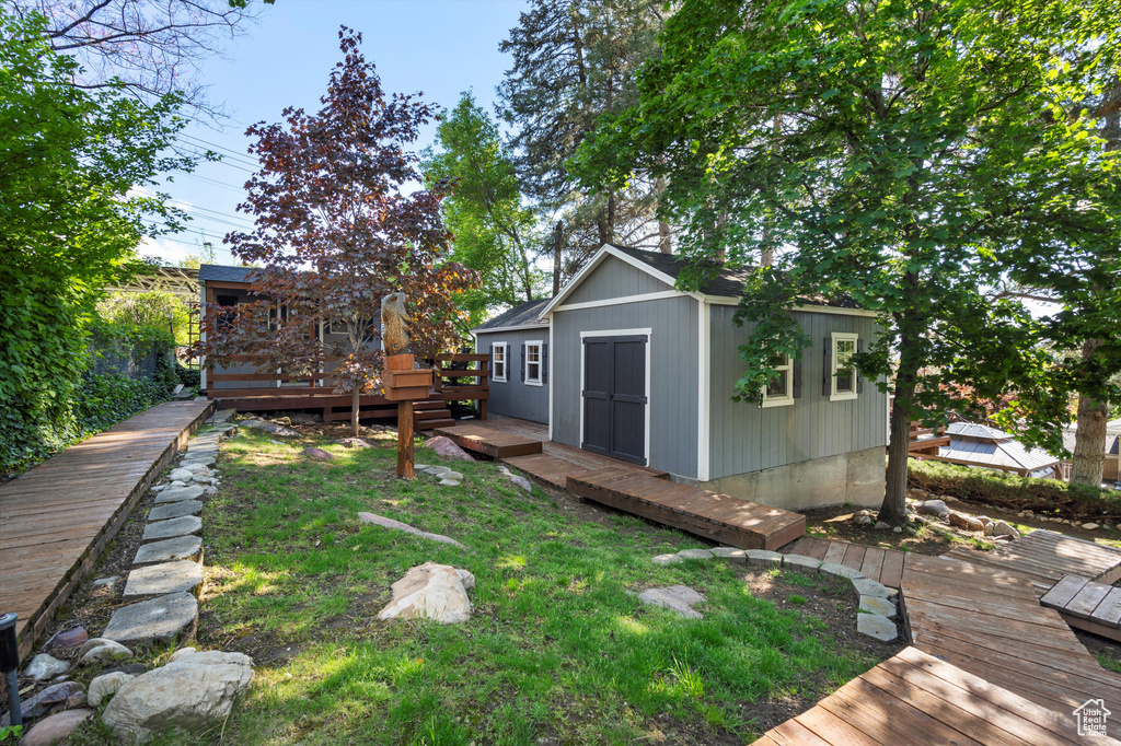 View of grassy yard featuring a deck, an outbuilding, and a storage unit