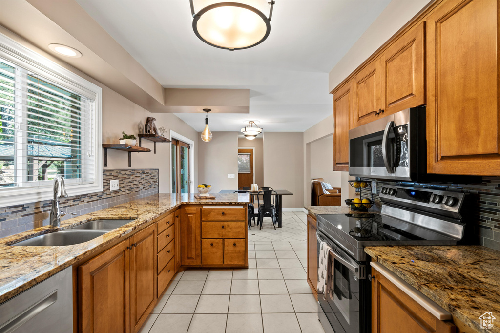 Kitchen featuring appliances with stainless steel finishes, a sink, brown cabinets, and backsplash