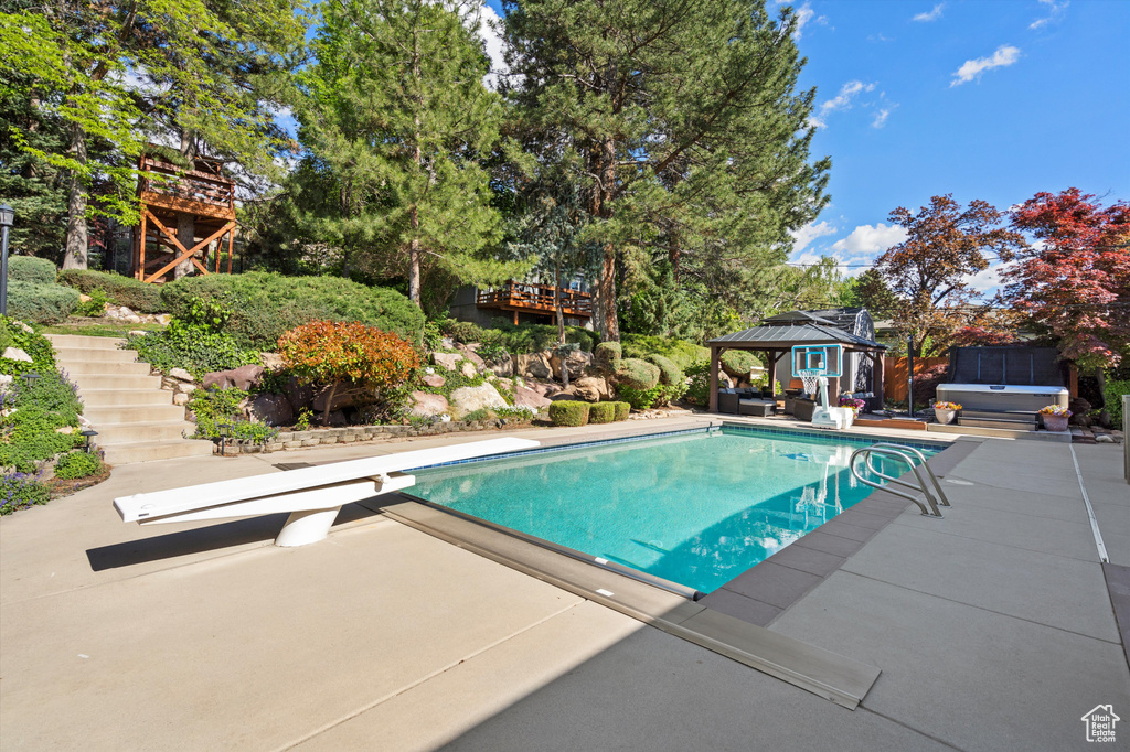 Swimming pool with a jacuzzi, a gazebo, a diving board, stairway, and a patio