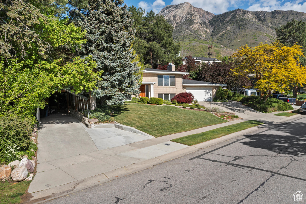 View of front of house featuring a front lawn, a mountain view, a chimney, and brick siding