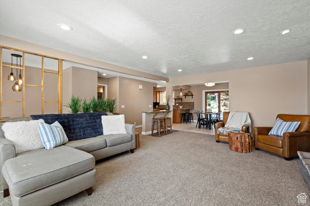 Carpeted living area with a textured ceiling, recessed lighting, and baseboards