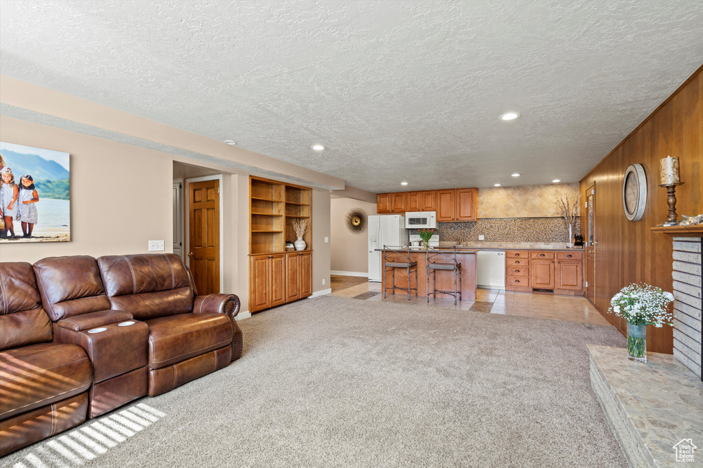 Living area with a textured ceiling, recessed lighting, baseboards, and light carpet