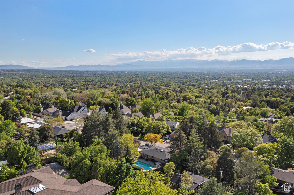 Aerial view of residential area with mountains, a heavily wooded area, and a pool area
