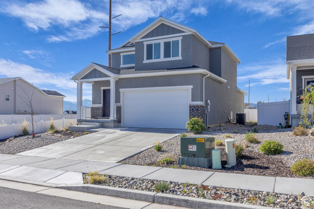 View of front of home featuring fence, a garage, central AC unit, concrete driveway, and stucco siding
