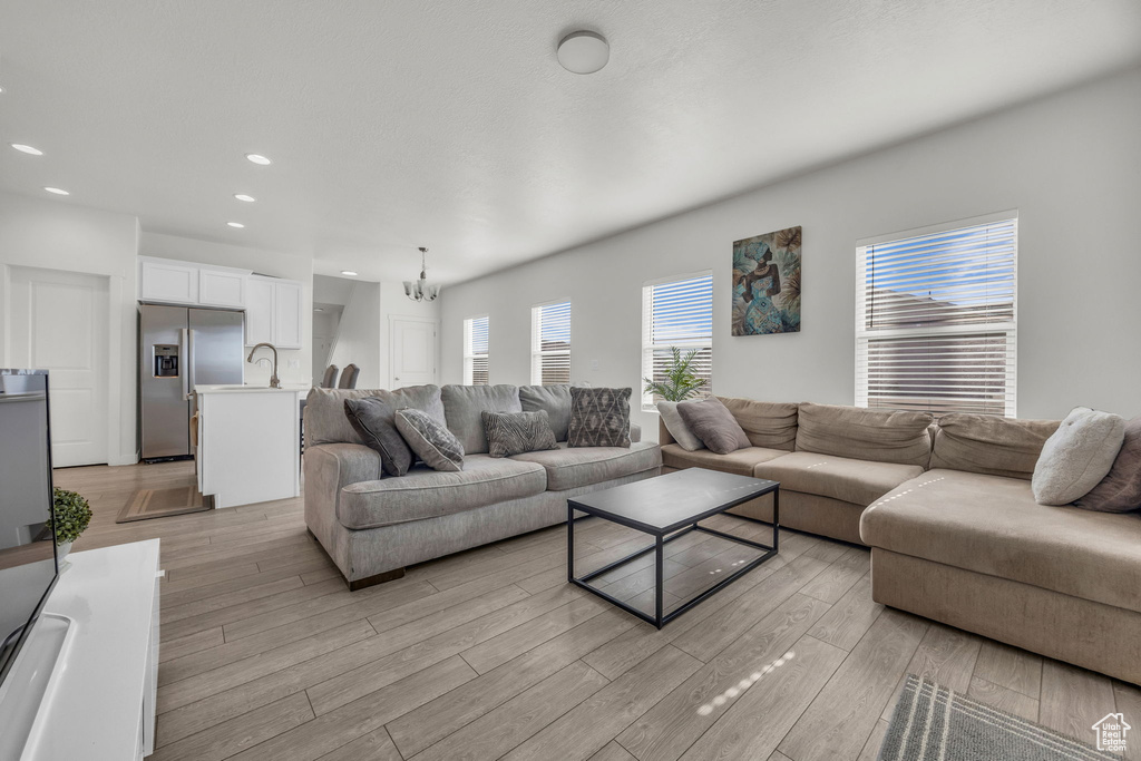 Living room with light wood-style flooring, recessed lighting, and a chandelier